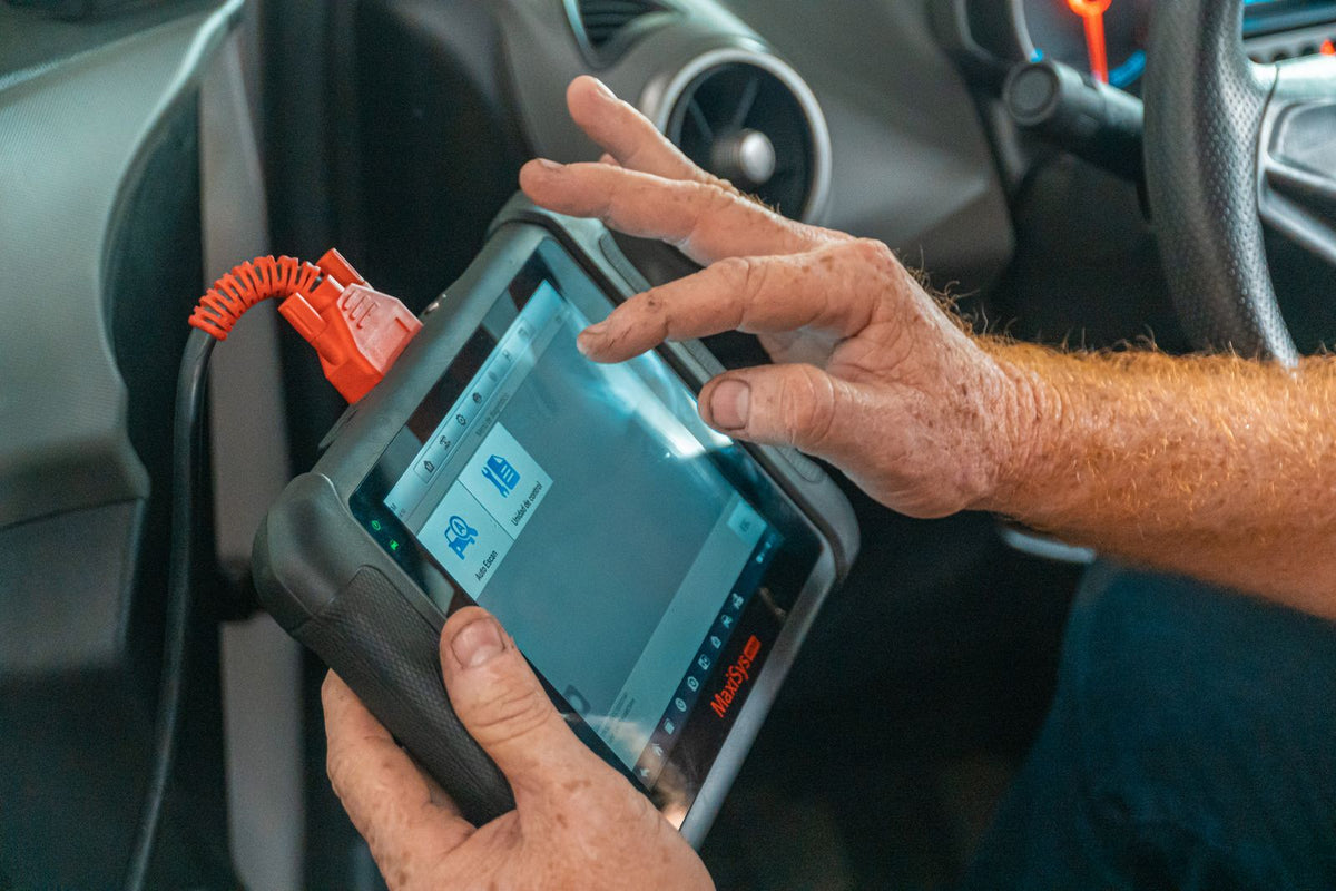 Técnico revisando un vehículo con una tableta de diagnóstico